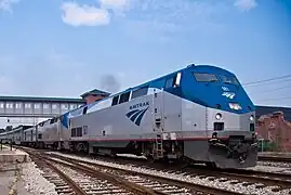 A gray diesel locomotive with a blue roof and a thin red sill stripe