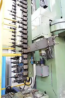 A chain type automatic tool changer with swiveling arm and two grippers, installed on a mill