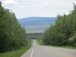 Chena Hot Springs Road at mile 14 (km 22), looking westbound and downhill with the Little Chena River valley at the bottom.
