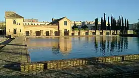 Reservoir of the al-Buḥayra gardens in Seville, with remains of palace structure behind it (partly occupied by later building)